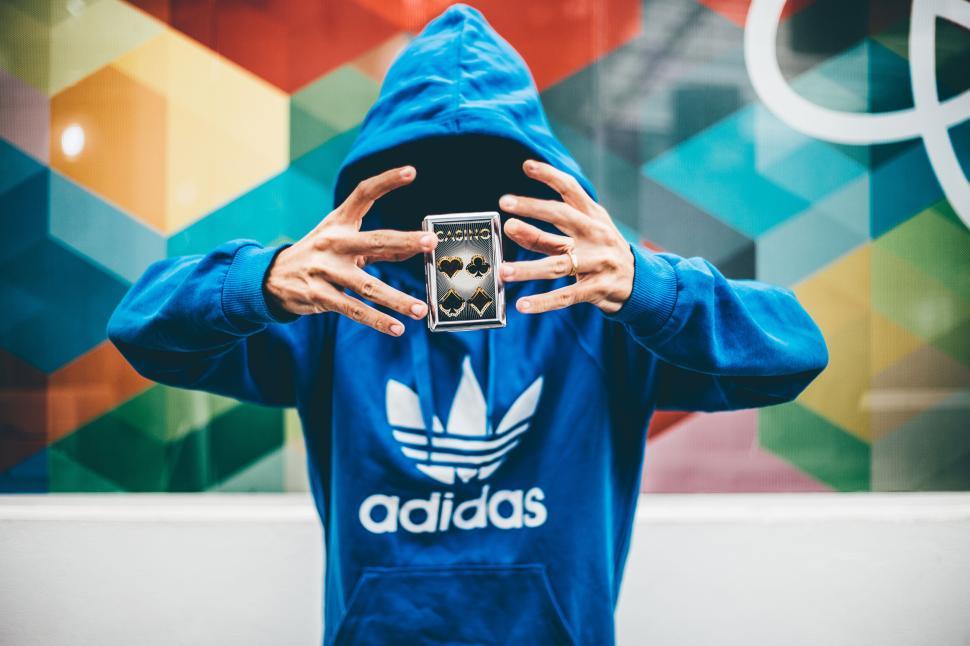 Free Image of Person in blue hoodie displaying cards with creative colorful wall. 