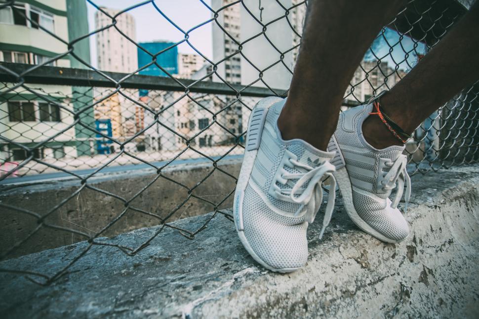 Free Image of Close-up of person’s feet in white sneakers on urban rooftop edge. 