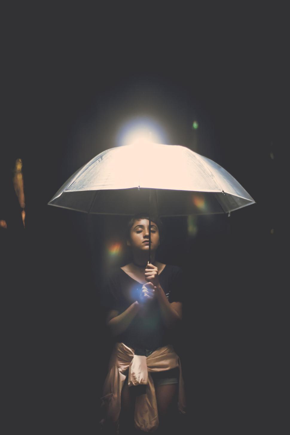 Free Image of Woman under illuminated umbrella in low light setting 