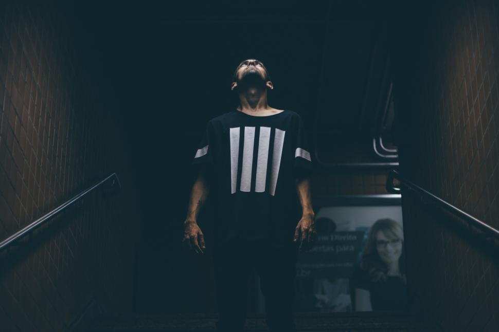 Free Image of Person standing on stairs in dark subway station with modern art 