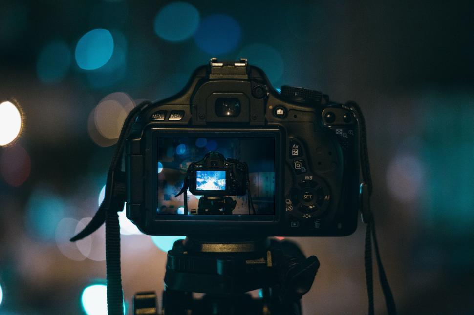 Free Image of Camera on tripod capturing city lights reflection during night time. 
