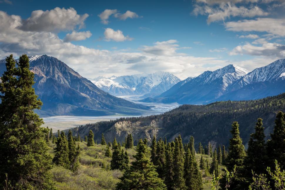 Free Image of Majestic snowy mountains rise above a lush green valley scenic view. 