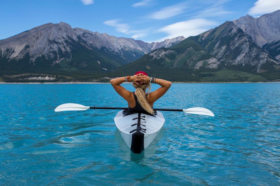 Free Image of Woman kayaking on turquoise lake surrounded by mountain landscape. 