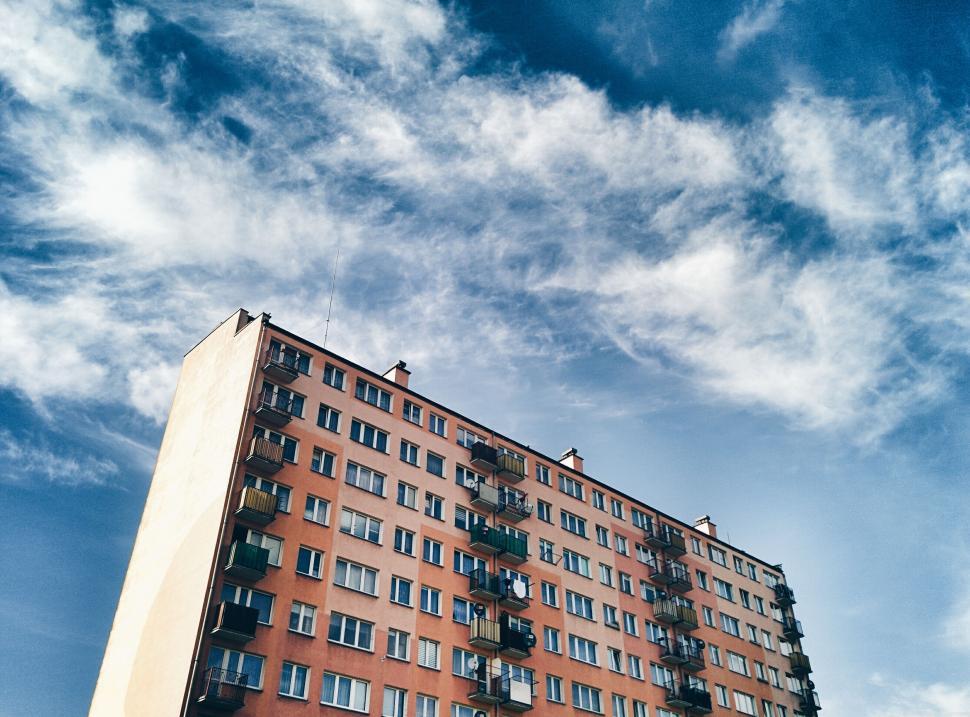 Free Image of Tall apartment building under a beautiful blue sky with clouds 