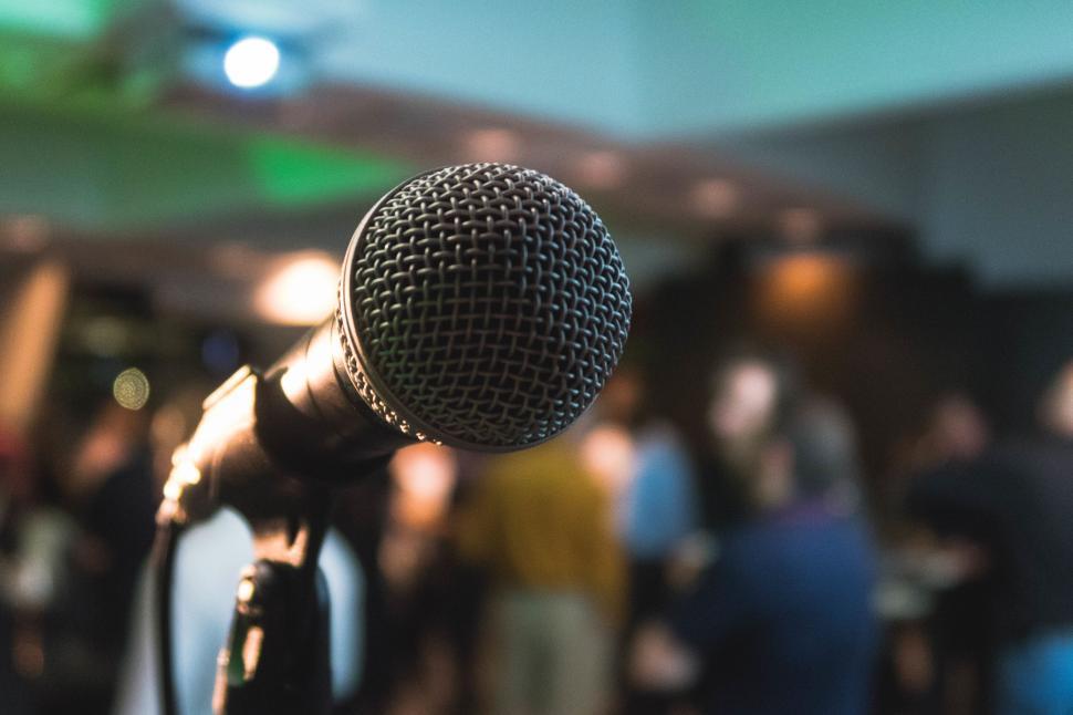 Free Image of Microphone on stage in front of blurred audience, close-up view 