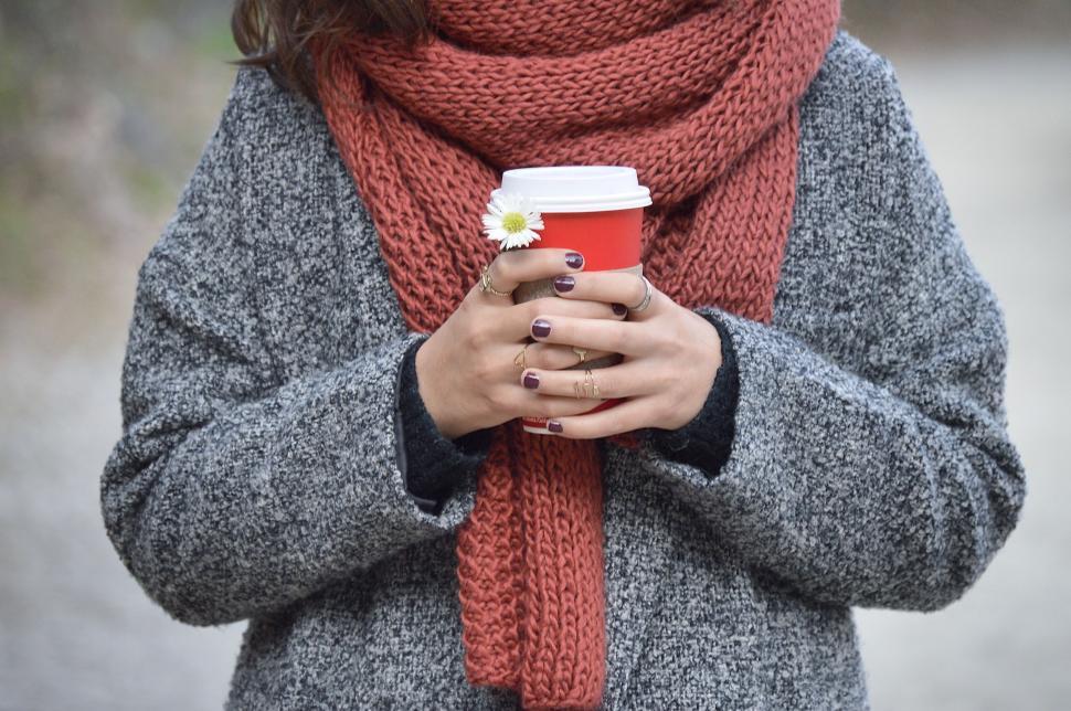 Free Image of Woman in winter attire holding a hot drink cup, outdoors scenic view 