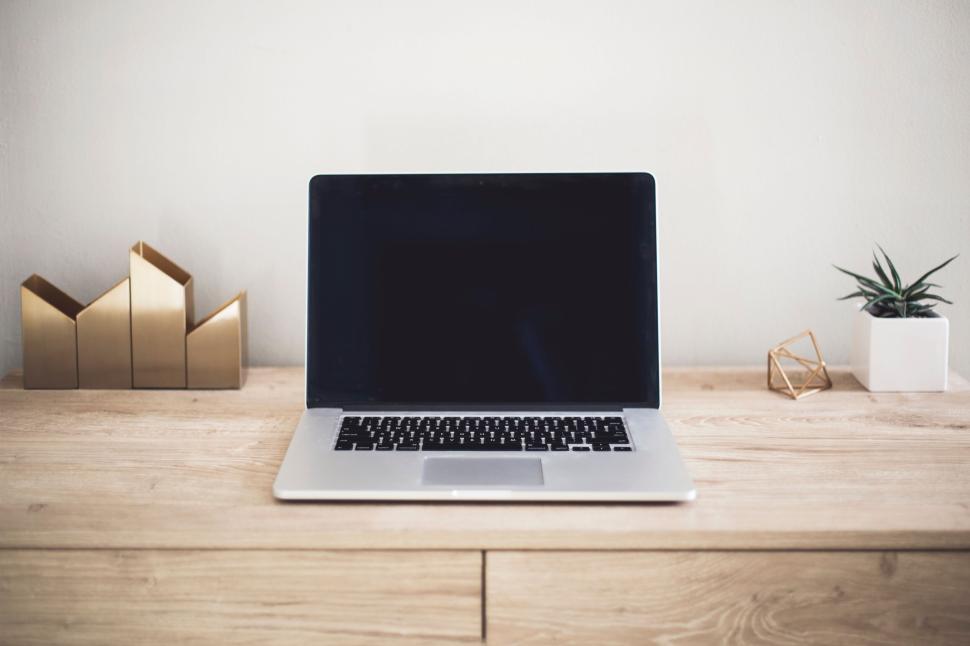 Free Image of Laptop on wooden desk with decorations and a small plant pot. 