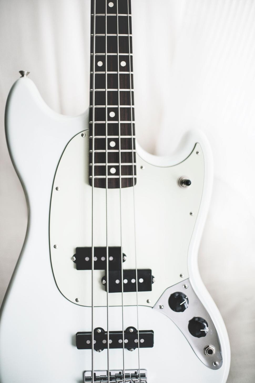 Free Image of White electric bass guitar with detailed neck and body design. 