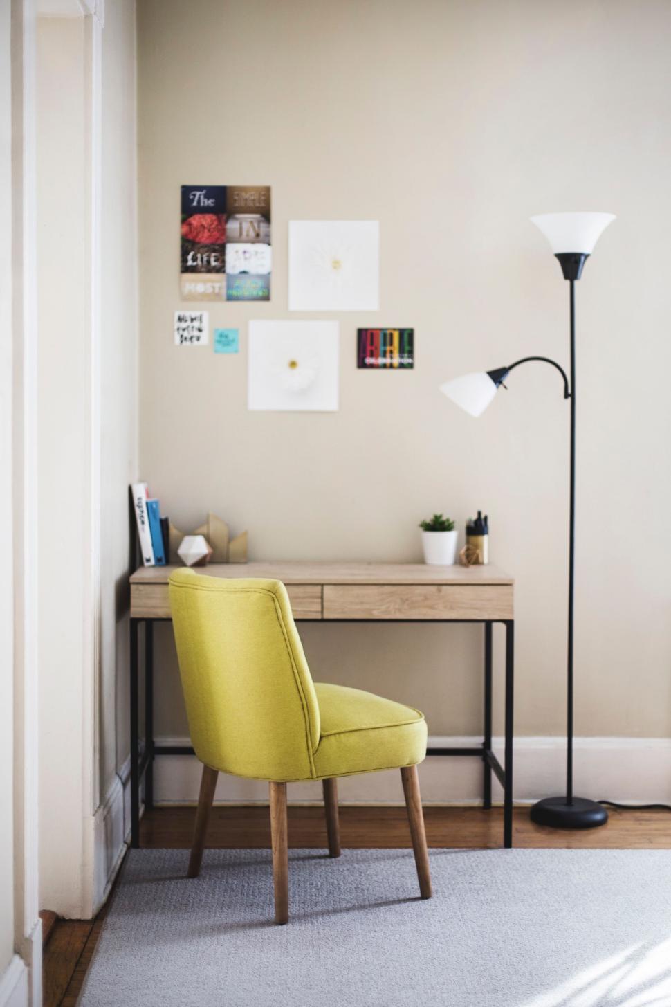 Free Image of Minimalist workspace with a yellow chair and wall decorations. 