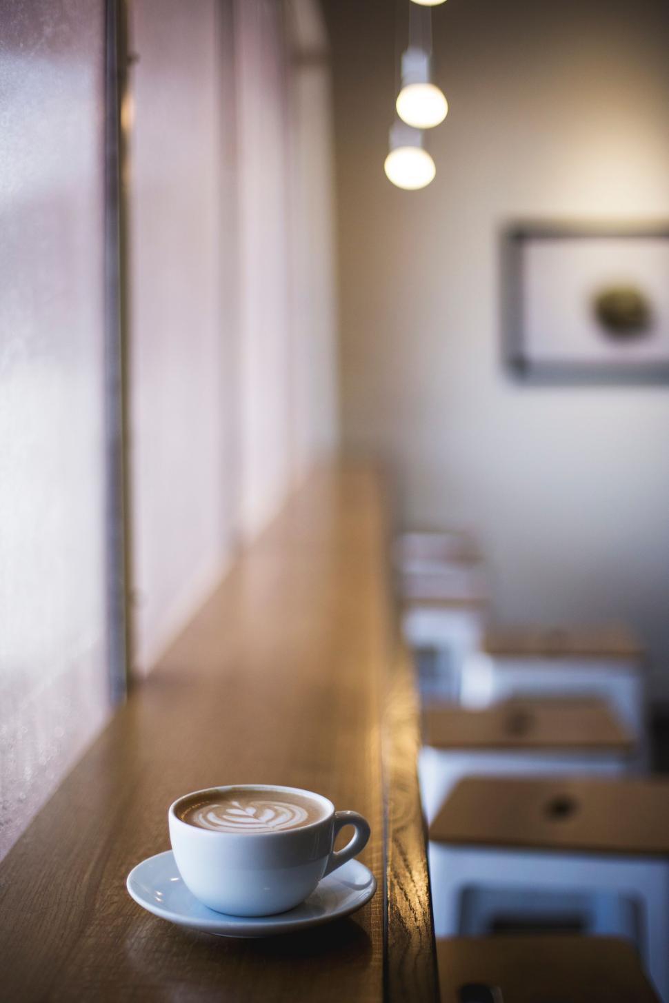 Free Image of Cup of cappuccino with latte art on a wooden counter in a cafe 