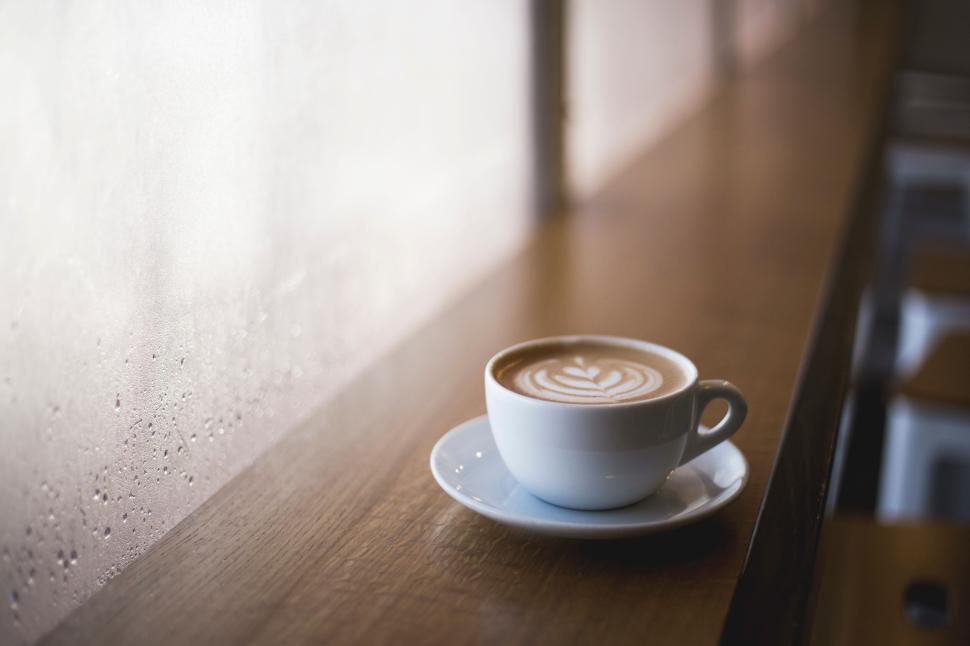 Free Image of Cup of coffee with latte art on a wooden counter in soft light 
