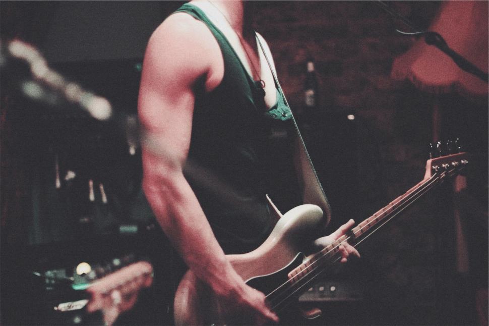 Free Image of Musician playing electric guitar in dimly lit moody atmosphere. 