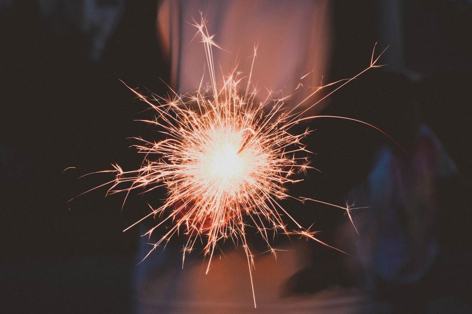 Free Image of Hand holding sparklers creating bright and dynamic light trails 
