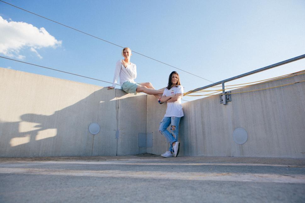 Free Image of Two people leaning against a wall, casting long shadows 