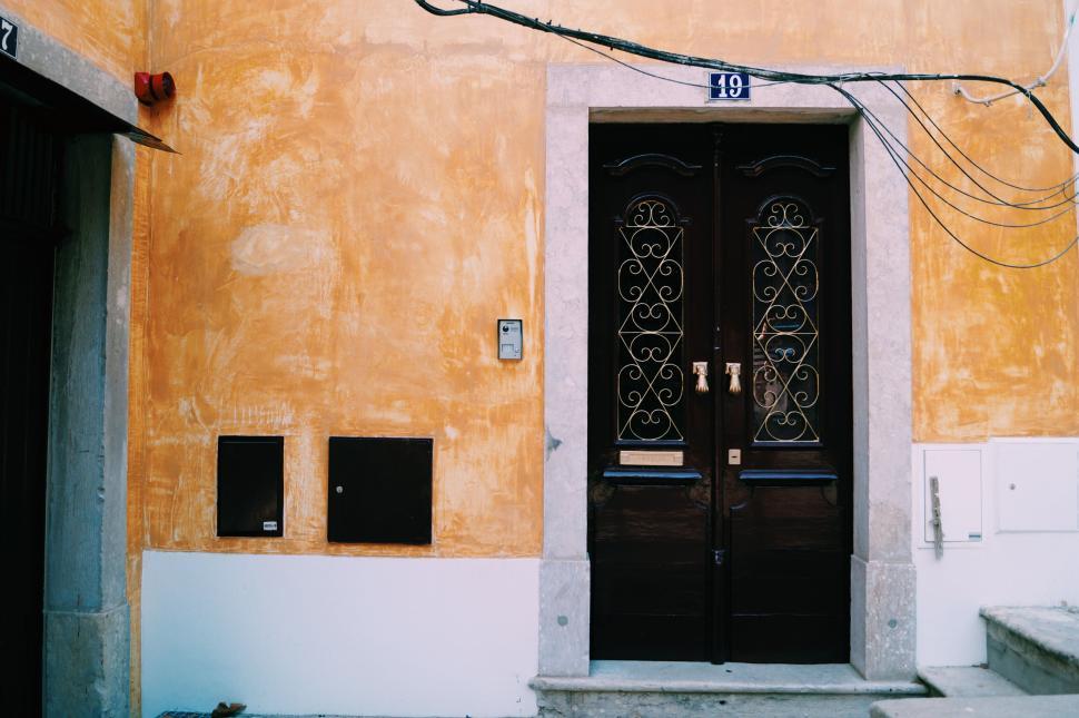 Free Image of Vintage wooden double door with intricate patterns on orange wall 