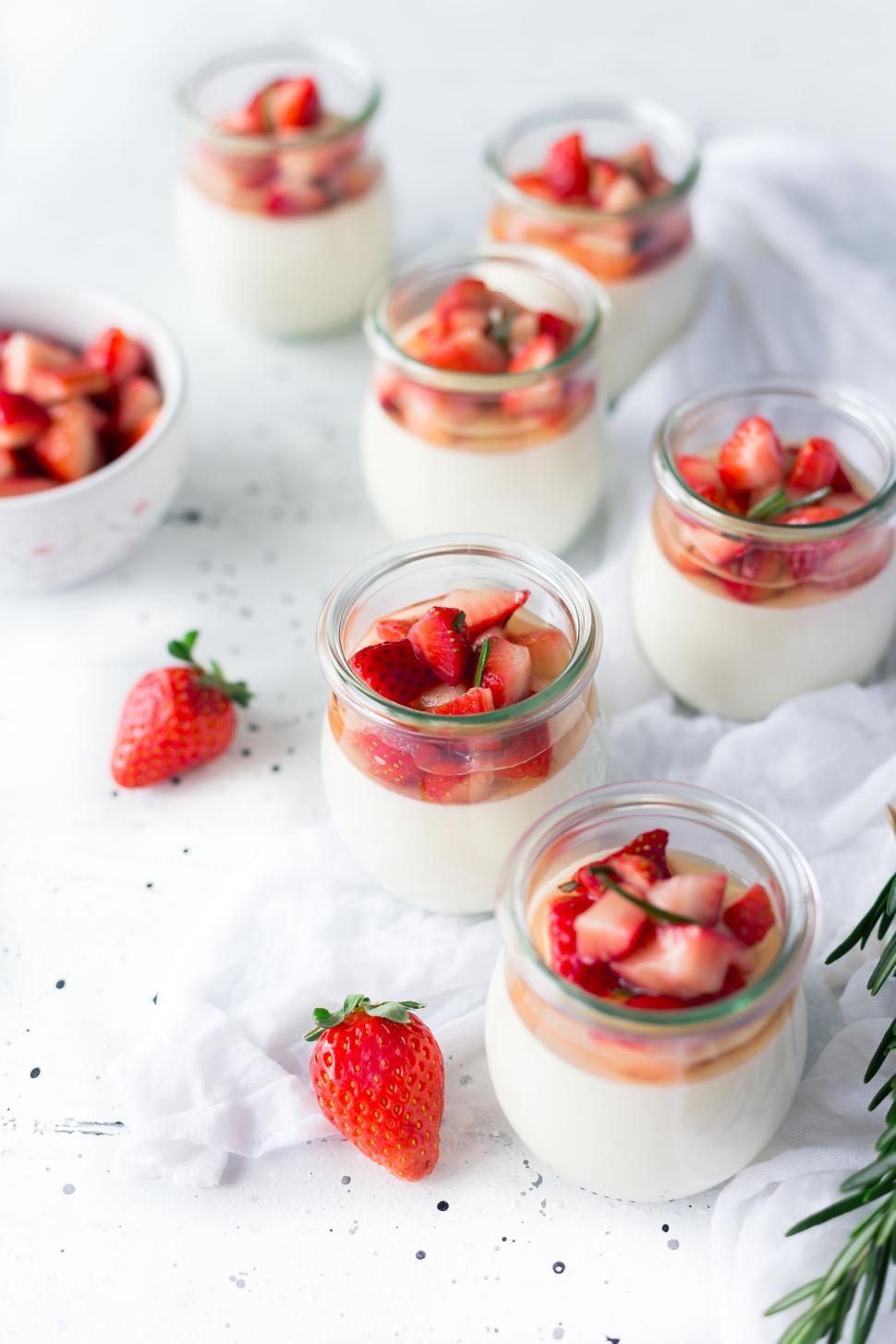 Free Image of Glass jars of panna cotta topped with fresh strawberry slices 