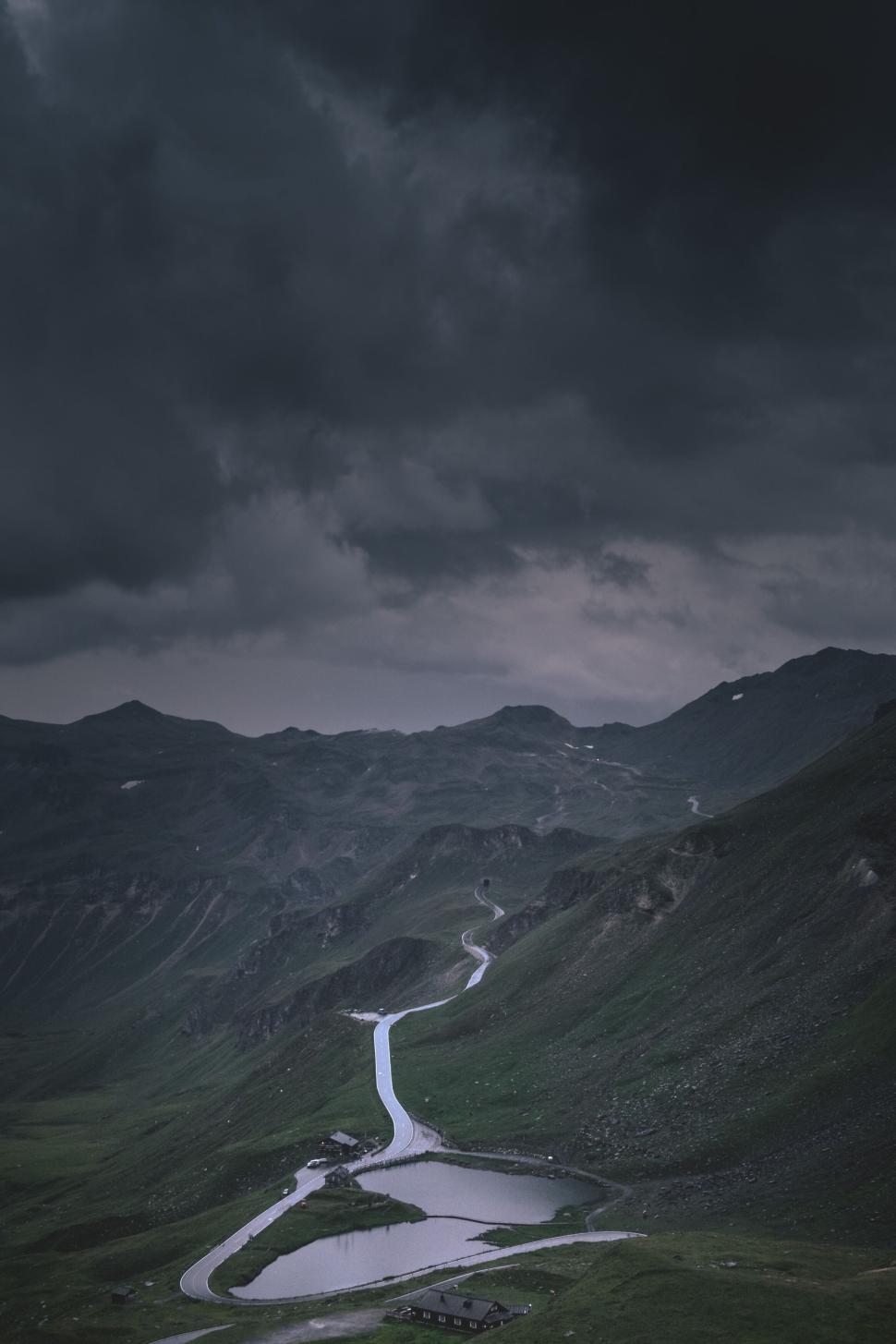 Free Image of Winding road through mountainous terrain under dark moody skies. 