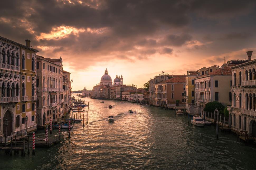 Free Image of Venetian canal bustling with boats and historic buildings at sunset. 