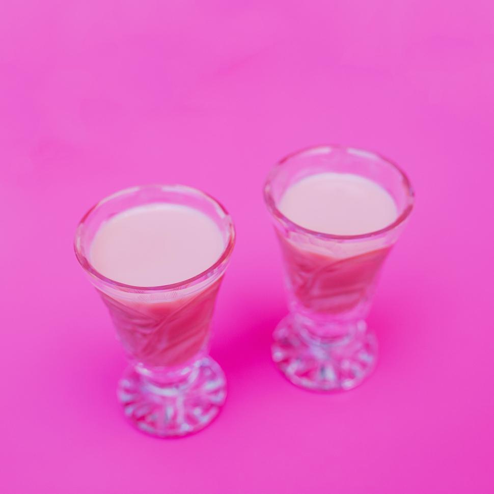 Free Image of Two glasses of pink milkshake on bright pink background, vibrant image. 
