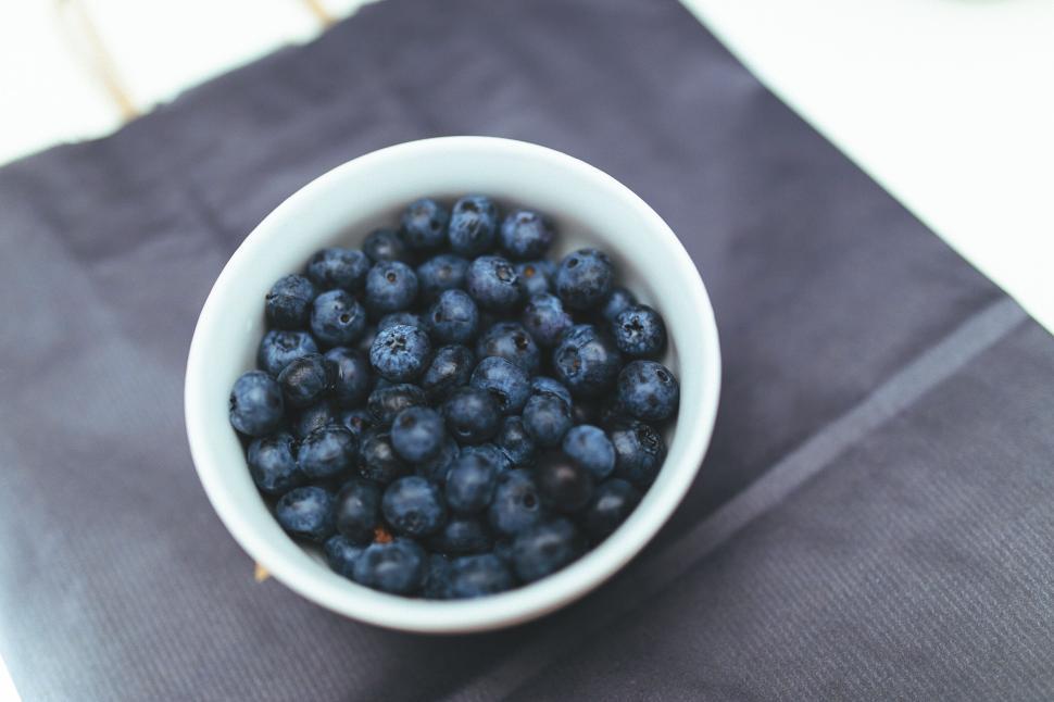 Free Image of A bowl of fresh blueberries displayed on a dark fabric cloth 