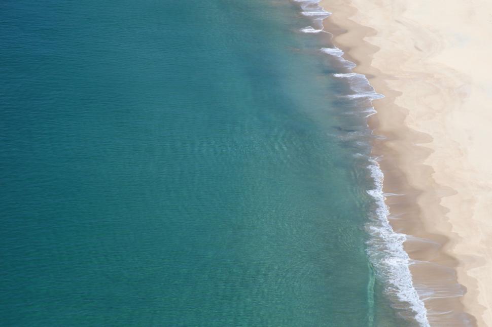 Free Image of Aerial view of a pristine beach with clear turquoise ocean water. 