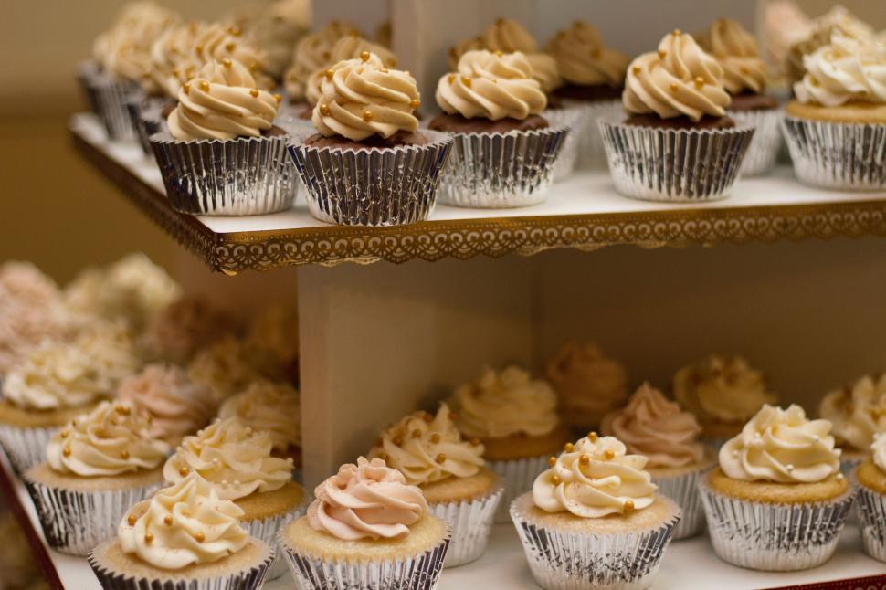 Free Image of Cupcakes with various icing, neatly arranged on tiered display stand 