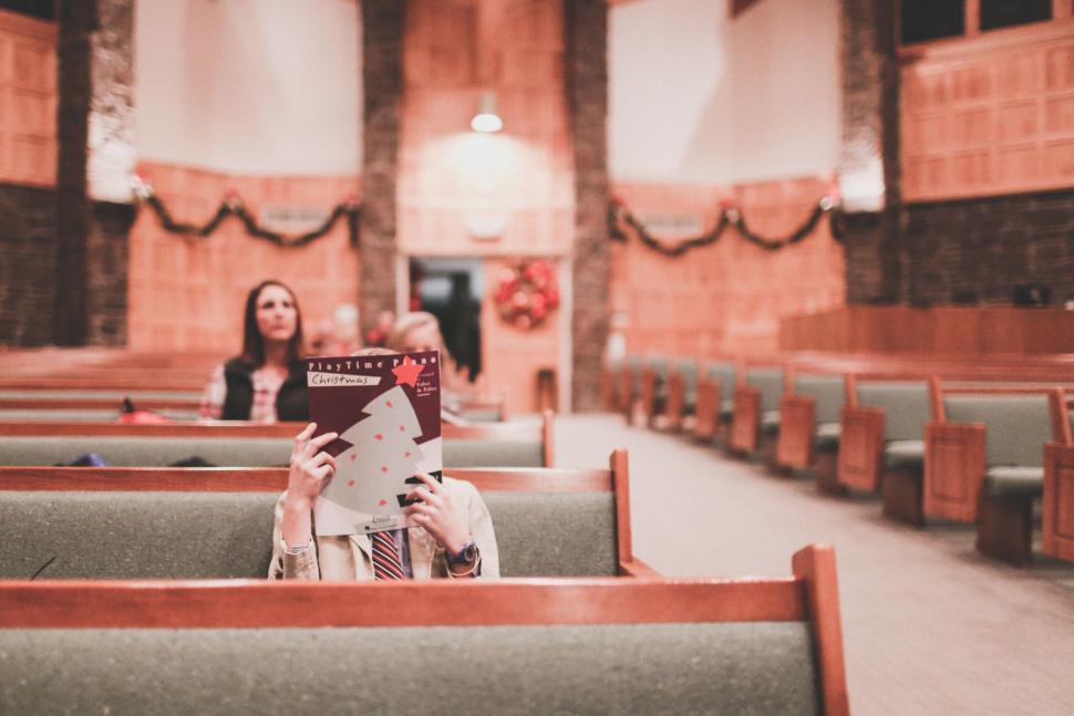 Free Image of Person reading sheet music in a festive decorated church pew. 