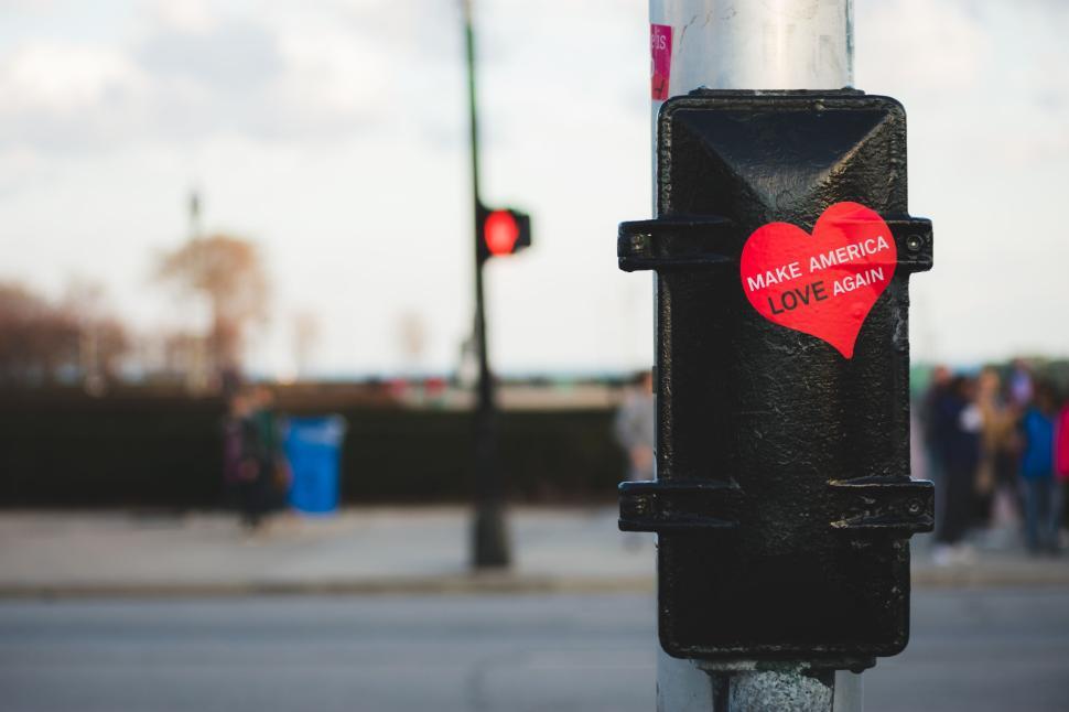 Free Image of Red heart sticker on streetlight pole with an urban background 