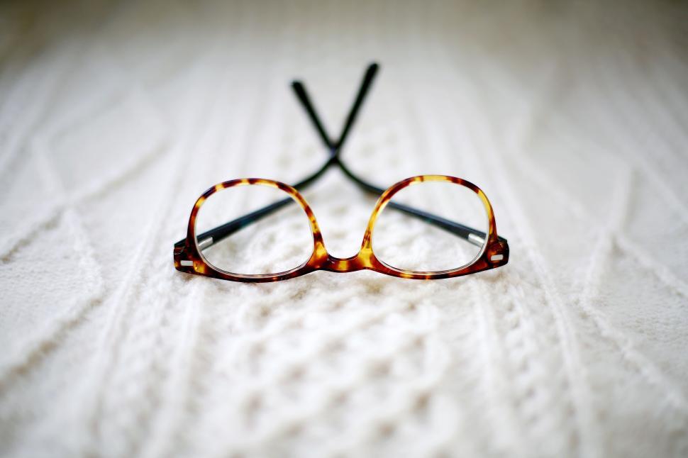 Free Image of Tortoiseshell glasses on cable-knit fabric surface with focus. 