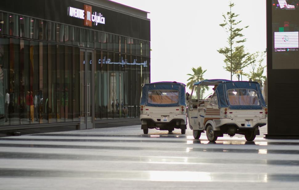 Free Image of Modern outdoor market scene with vehicles parked in foreground. 