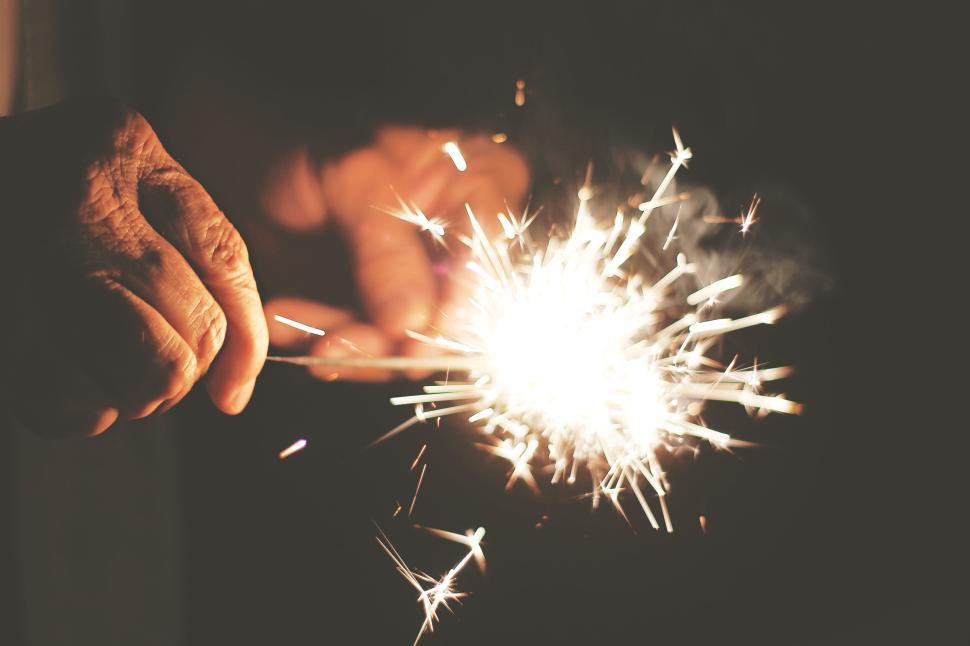 Free Image of Hands holding sparklers emitting bright sparks in the dark night 
