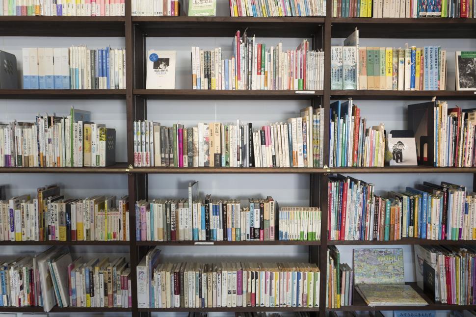 Free Image of Books neatly arranged on wooden bookshelves in a library setting. 