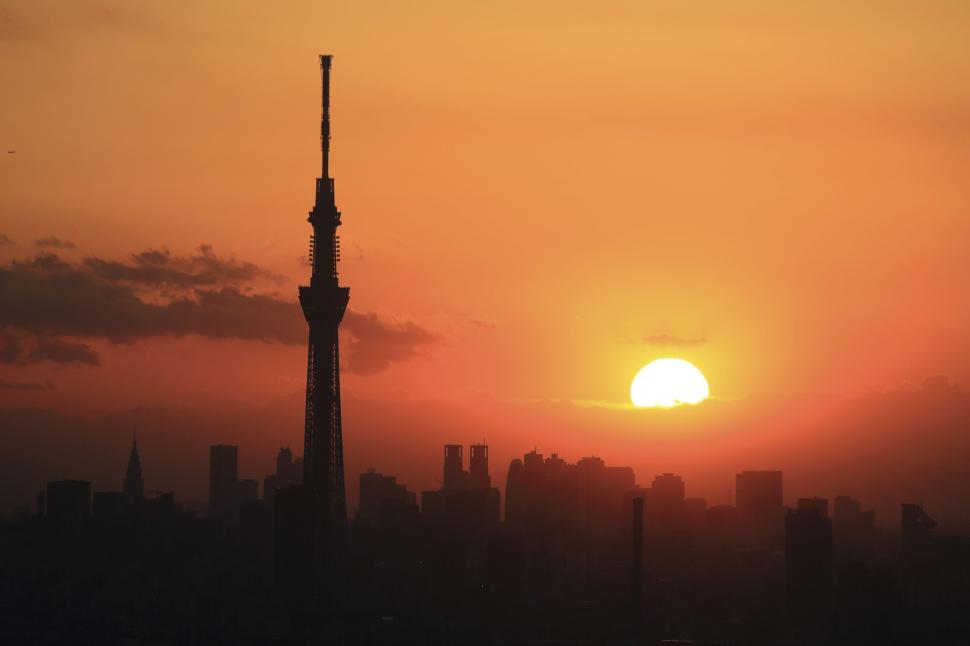 Free Image of Sunset behind prominent city tower, capturing urban silhouette 