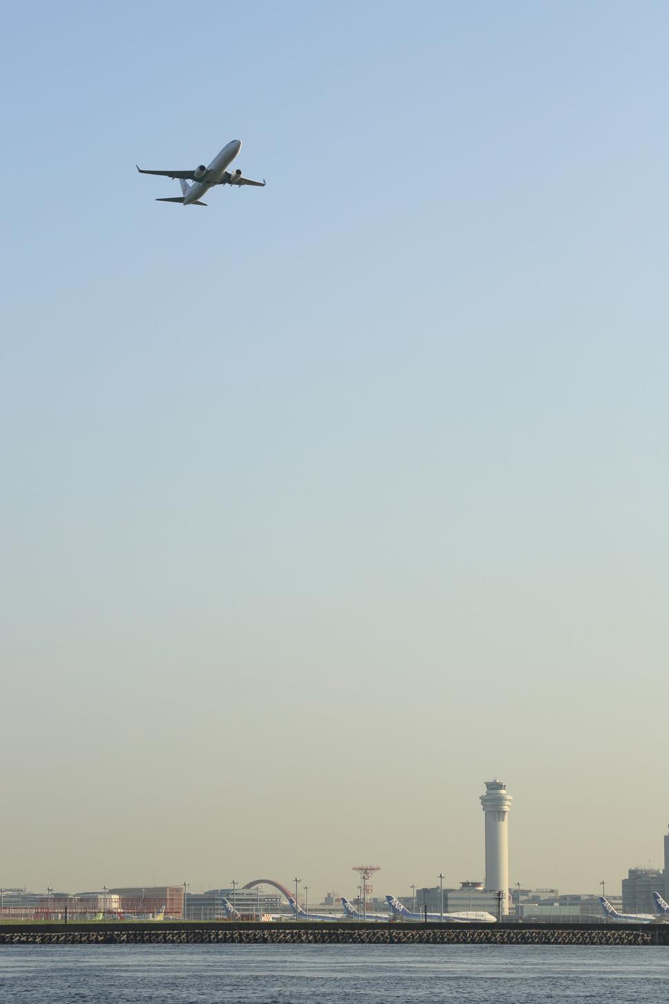 Free Image of Airplane ascending in clear sky above city airport and tower 