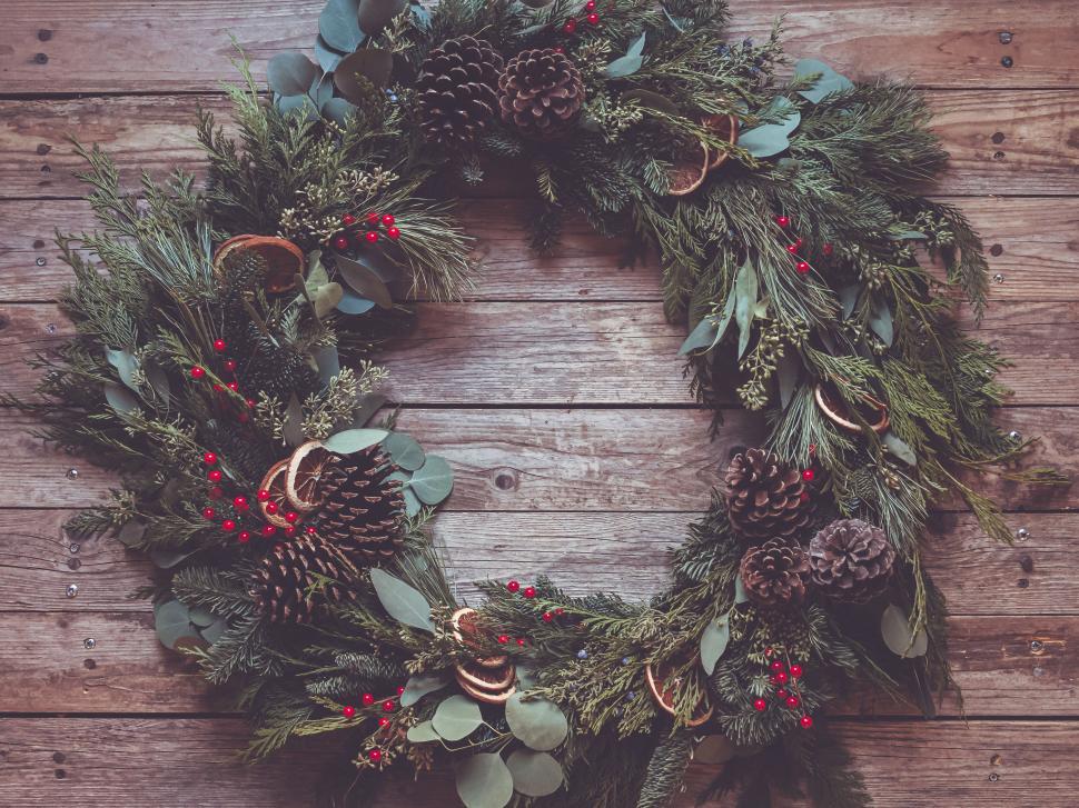 Free Image of Festive Christmas wreath on rustic wooden background with pinecones. 