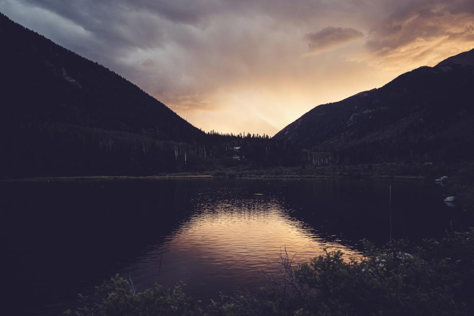 Free Image of Serene mountain lake during sunset with dramatic sky and reflections. 
