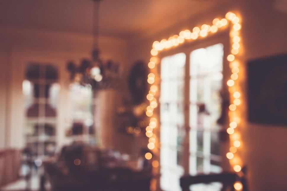 Free Image of Blurred dining room with fairy lights around windows at evening. 