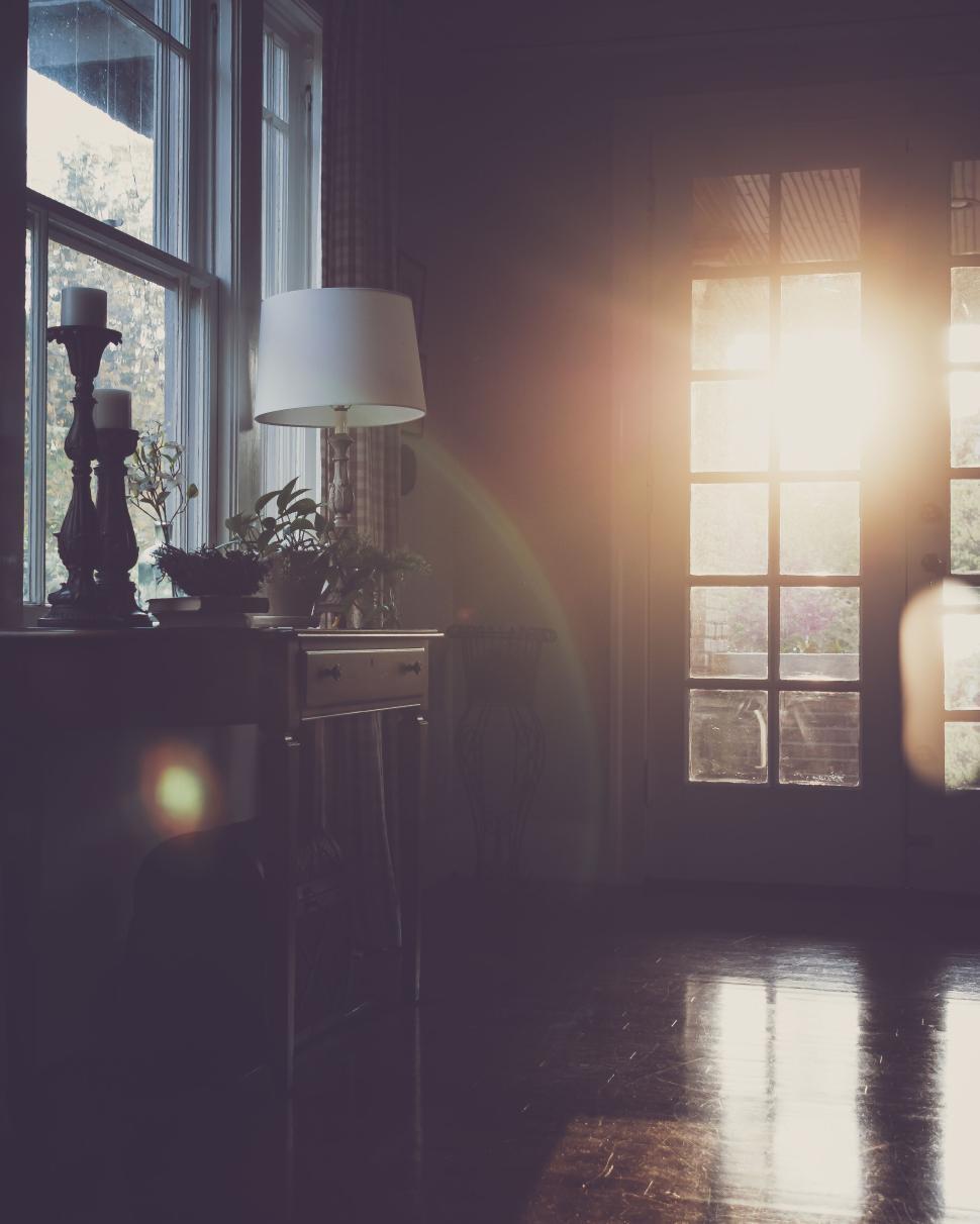 Free Image of Sunlight streaming through windows in a cozy, dimly lit room. 