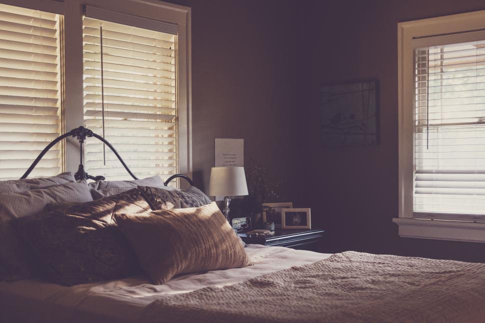 Free Image of Cozy bedroom with iron bed frame and sunlight streaming through blinds 