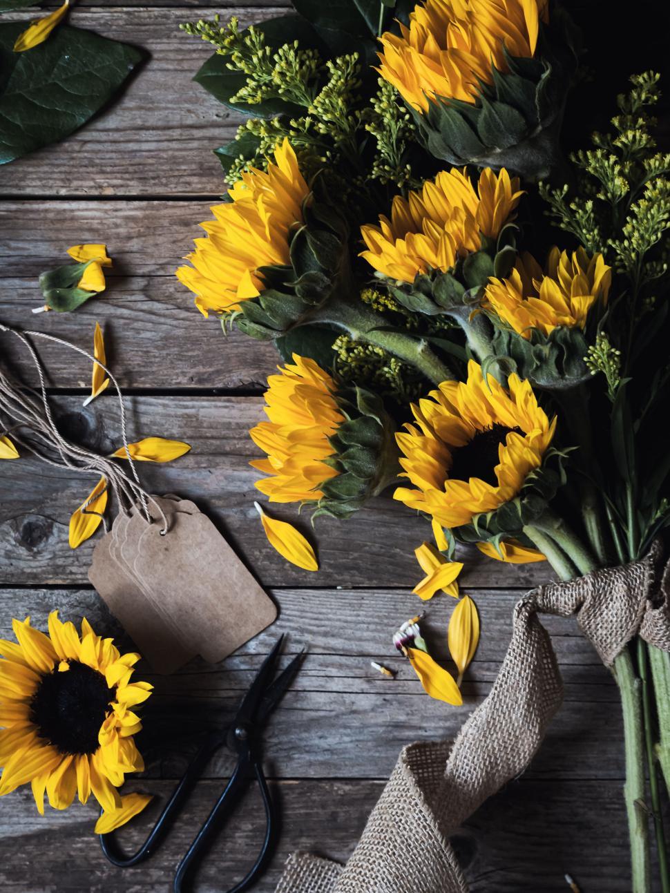 Free Image of Sunflower bouquet placed on rustic wooden background with tools 