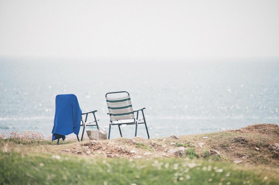 Free Image of Two empty chairs facing the ocean, creating a serene waiting moment. 