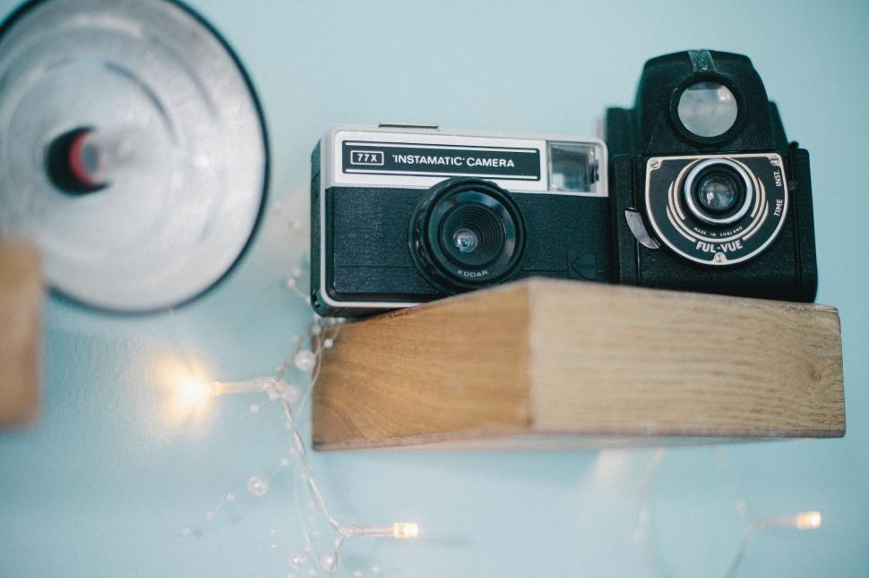 Free Image of Vintage cameras and light fixture on minimalist wooden shelf. 