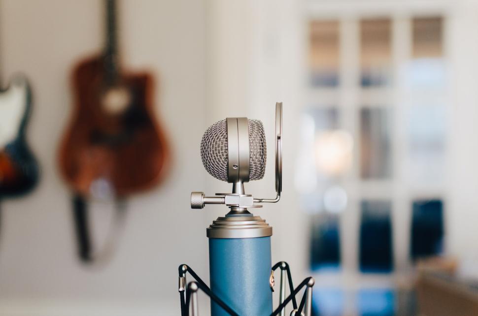 Free Image of Studio microphone with a guitar in the background, blurred. 