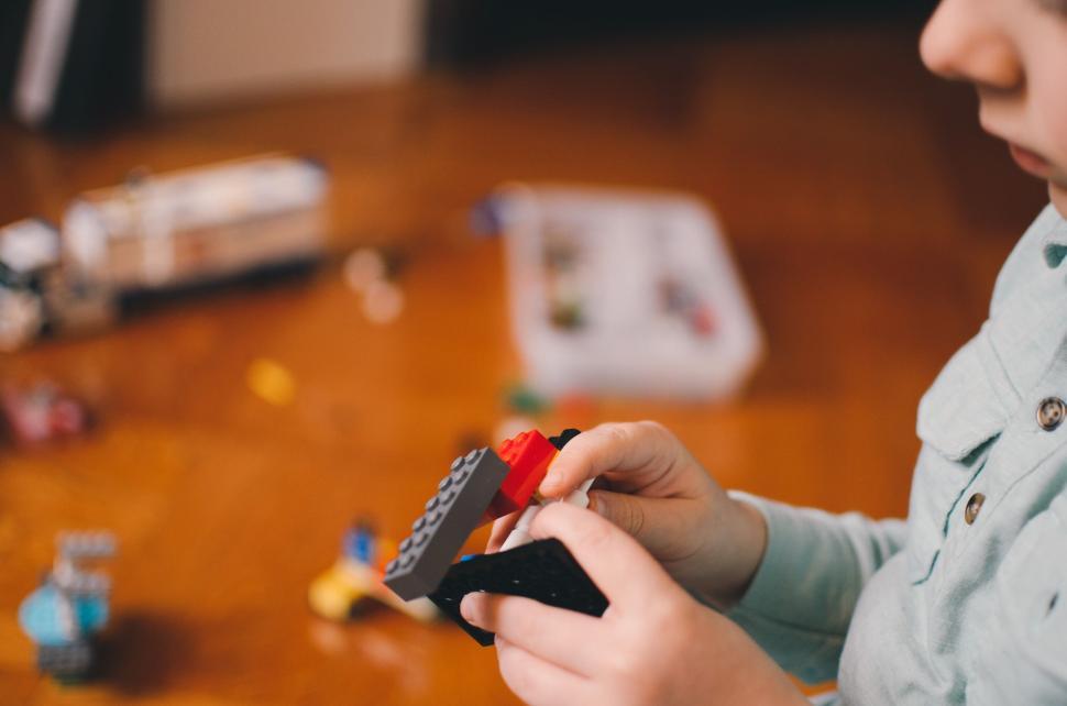 Free Image of Child s hands playing with colorful Lego bricks on a table. 