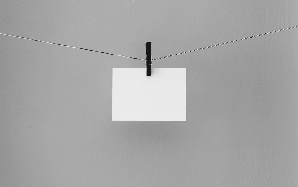 Free Image of Minimalist white card held by a clip on string in neutral background 