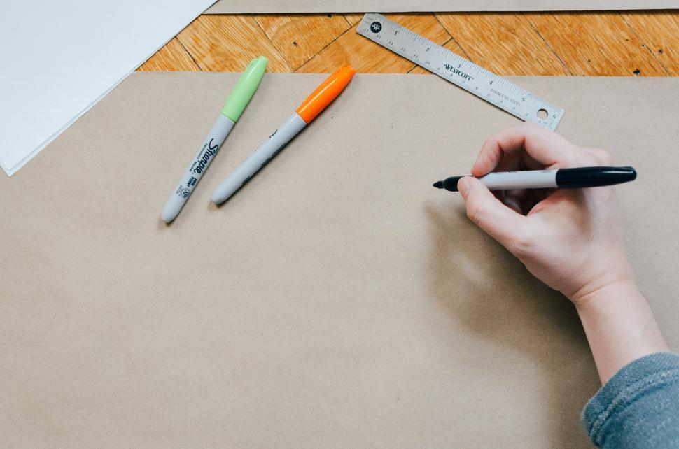 Free Image of Person drawing with black marker on a large piece of kraft paper. 
