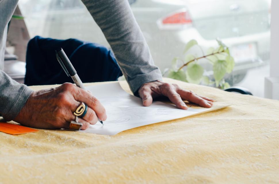 Free Image of Person sketching on paper with a mechanical pencil on a table top. 