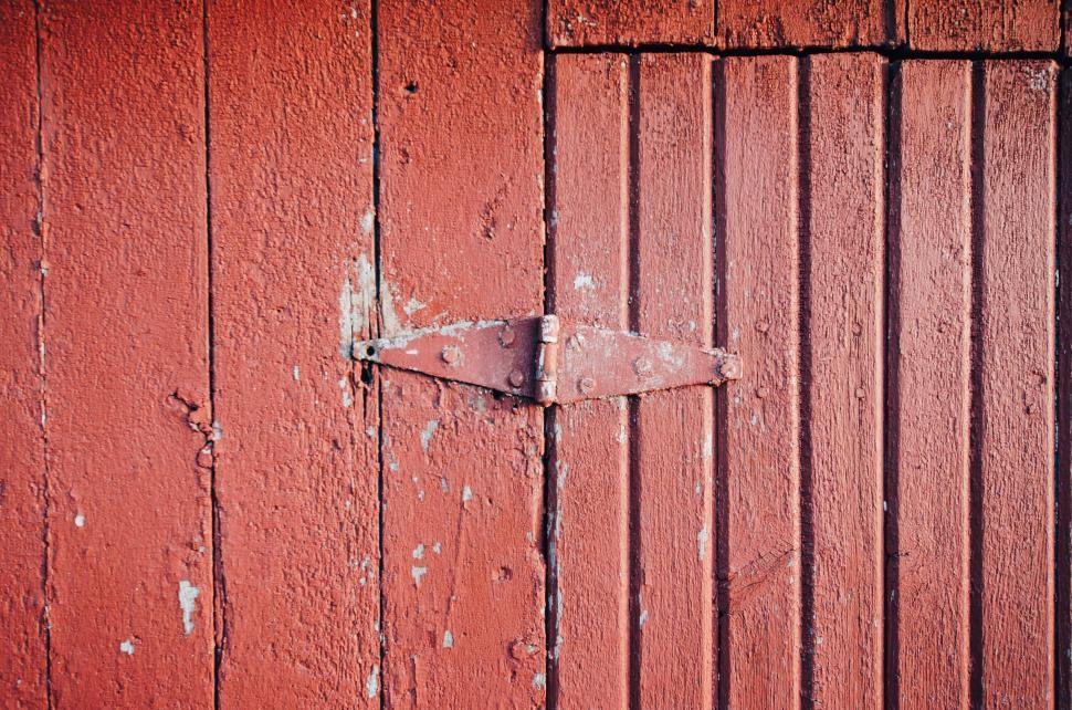Free Image of Close-up view of a red wooden door hinge on a weathered wood surface. 