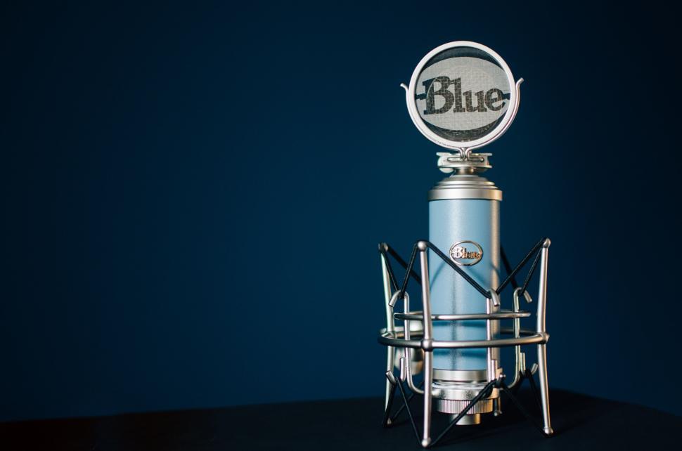 Free Image of Blue condenser microphone on a black surface with a blue background. 