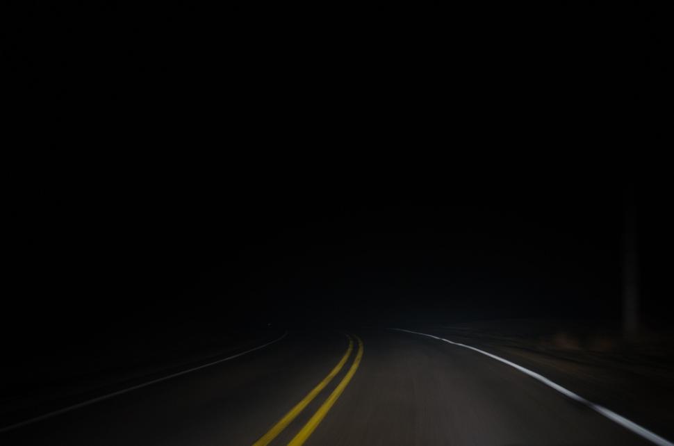 Free Image of Dark road at night illuminated by headlights with yellow dividing lines. 